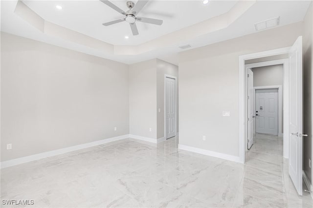 unfurnished bedroom featuring a raised ceiling and ceiling fan