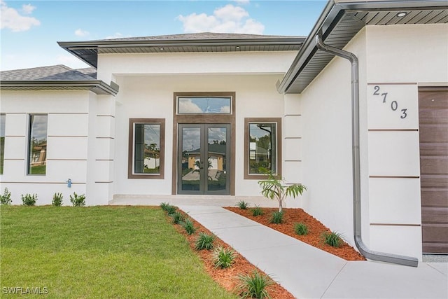 view of exterior entry with a yard and french doors