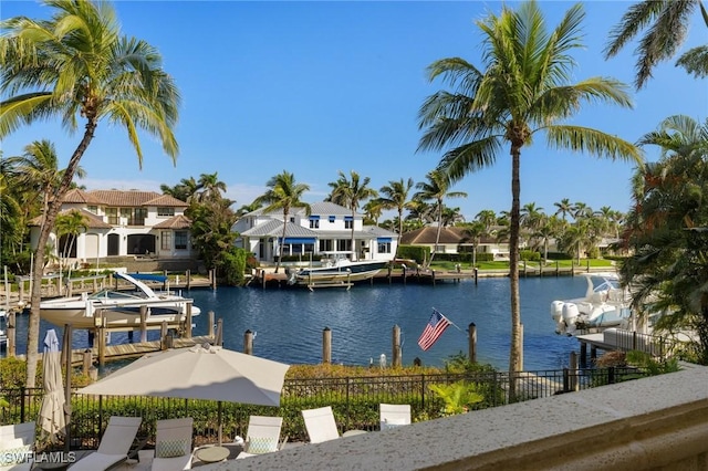 exterior space with boat lift, fence, a water view, and a residential view