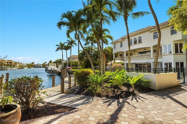 exterior space with a water view, a balcony, ceiling fan, and a boat dock