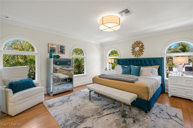 bedroom featuring wood finished floors, visible vents, and crown molding