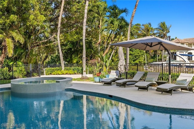 view of pool with a pool with connected hot tub, fence, and a patio