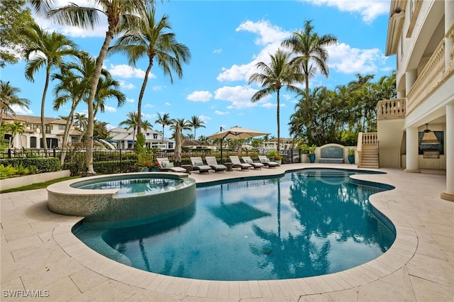 view of swimming pool with a pool with connected hot tub, fence, and a patio