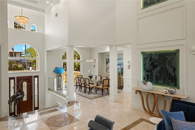 foyer entrance with crown molding, a towering ceiling, and baseboards