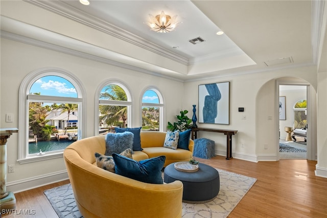 sitting room with arched walkways, wood finished floors, a wealth of natural light, and crown molding