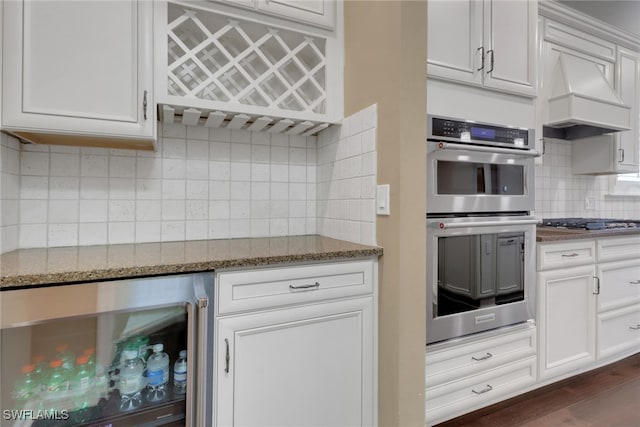 kitchen with premium range hood, white cabinetry, dark stone counters, wine cooler, and stainless steel appliances