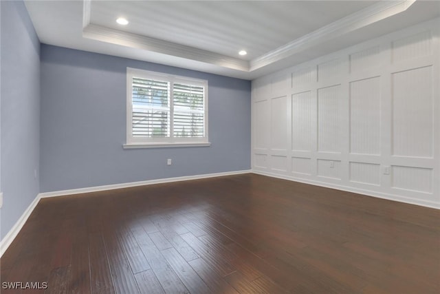 spare room with a tray ceiling, dark wood-type flooring, and ornamental molding