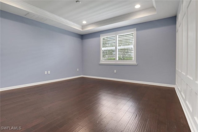 unfurnished room featuring a tray ceiling, dark wood-type flooring, and ornamental molding