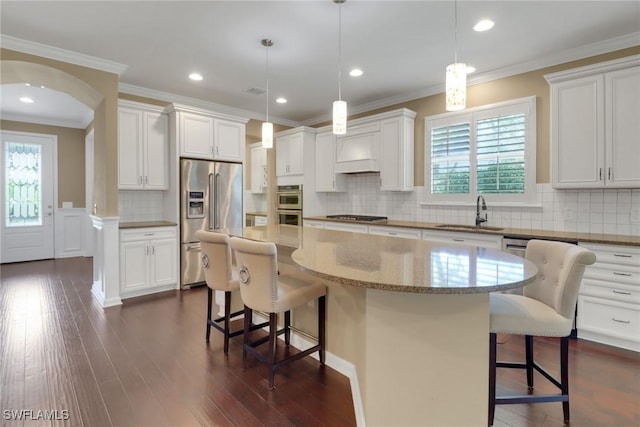 kitchen with appliances with stainless steel finishes, sink, hanging light fixtures, and a center island