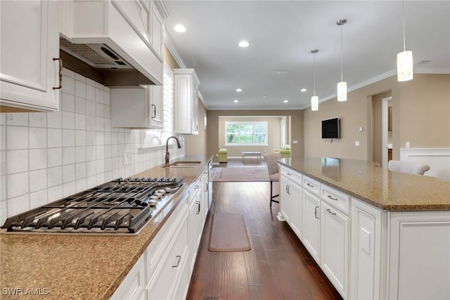 kitchen with sink, white cabinets, light stone countertops, and pendant lighting