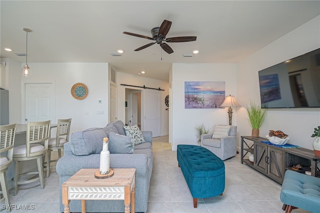 living room featuring ceiling fan, a barn door, and light tile patterned flooring