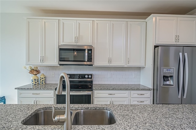 kitchen featuring white cabinetry, light stone countertops, sink, appliances with stainless steel finishes, and decorative backsplash