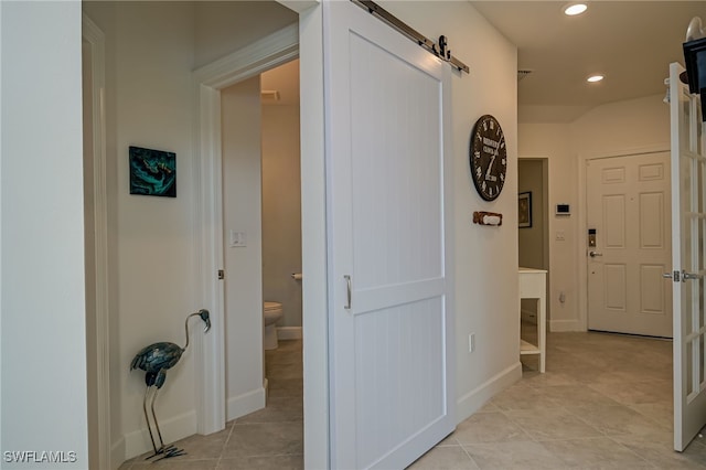 corridor with light tile patterned floors and a barn door