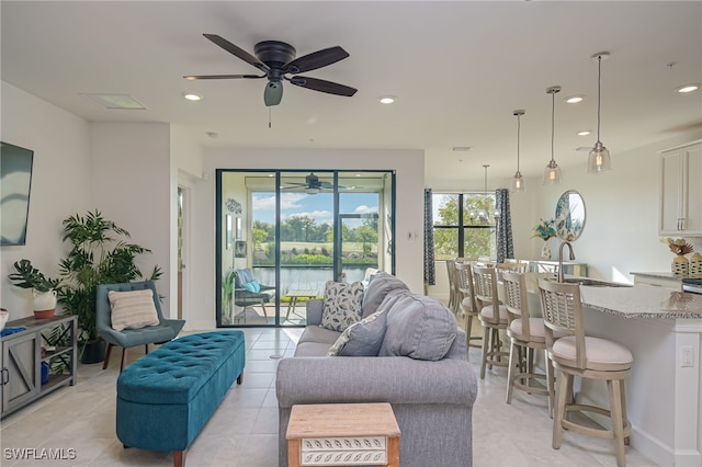 living room featuring sink, light tile patterned flooring, and ceiling fan