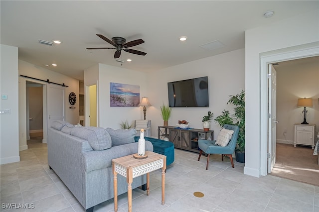 tiled living room featuring ceiling fan and a barn door