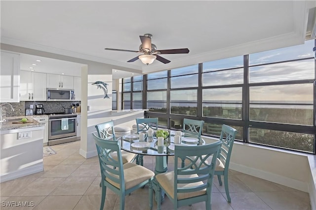 tiled dining space with sink, ornamental molding, and ceiling fan