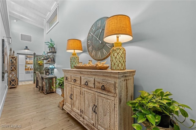 hall featuring a barn door, high vaulted ceiling, light wood finished floors, beamed ceiling, and baseboards