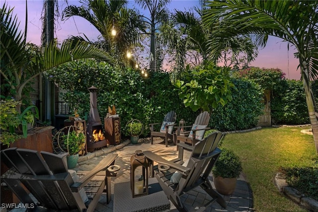 patio terrace at dusk featuring a yard