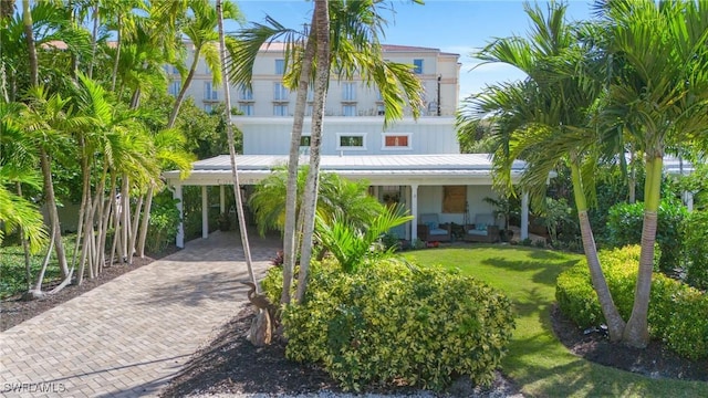raised beach house featuring an outdoor living space, a front yard, a carport, and decorative driveway