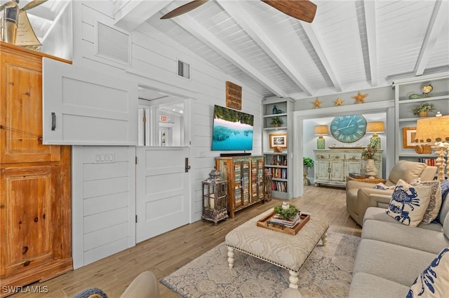 living area with beamed ceiling, visible vents, ceiling fan, and wood finished floors