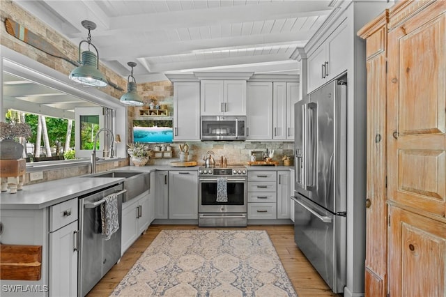 kitchen with light wood-style flooring, a sink, stainless steel appliances, beamed ceiling, and backsplash