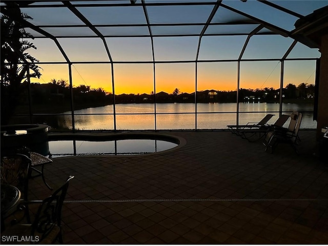 patio terrace at dusk with a water view and glass enclosure