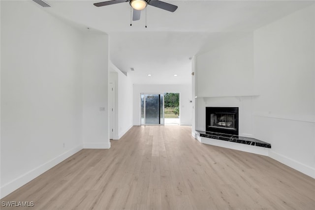 unfurnished living room with a tile fireplace, ceiling fan, and light wood-type flooring