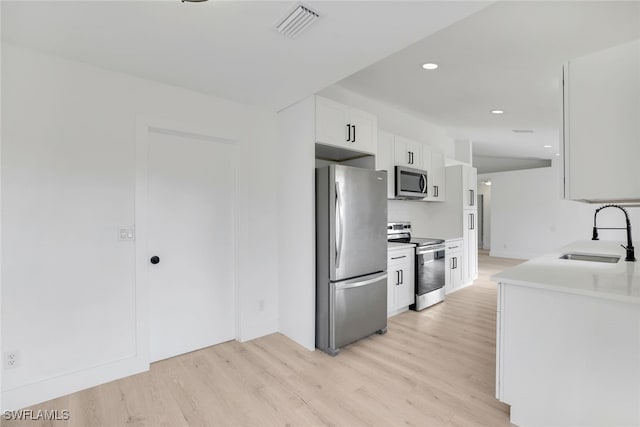 kitchen featuring sink, stainless steel appliances, light hardwood / wood-style floors, and white cabinets