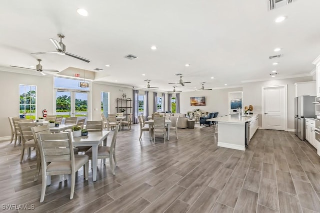 dining area featuring french doors, crown molding, a wealth of natural light, and light hardwood / wood-style flooring