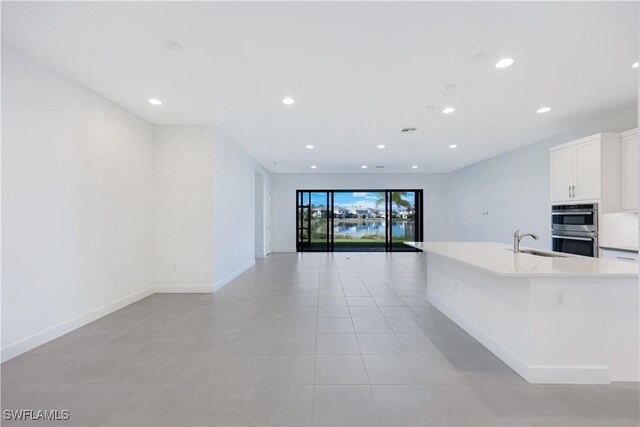 kitchen featuring recessed lighting, a sink, light countertops, white cabinetry, and double oven