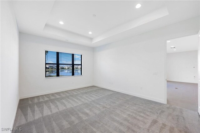 unfurnished room with a tray ceiling, recessed lighting, carpet, and baseboards