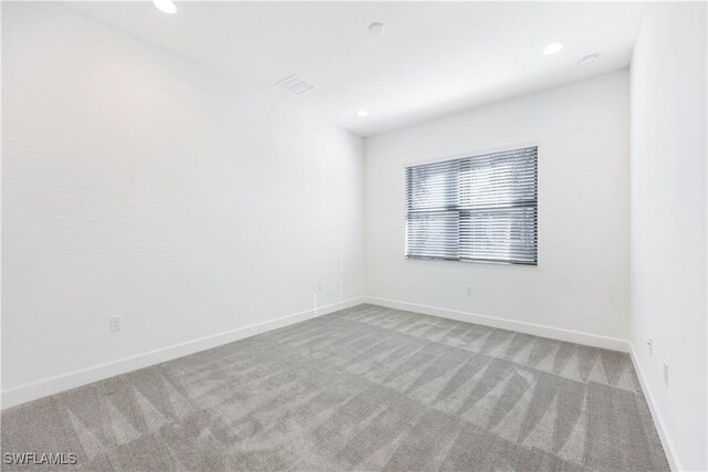 carpeted spare room featuring recessed lighting, visible vents, and baseboards