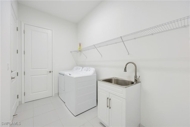 washroom featuring light tile patterned flooring, washer and dryer, cabinet space, and a sink