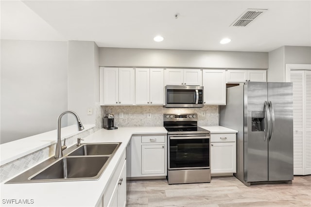 kitchen featuring stainless steel appliances, white cabinetry, sink, and decorative backsplash