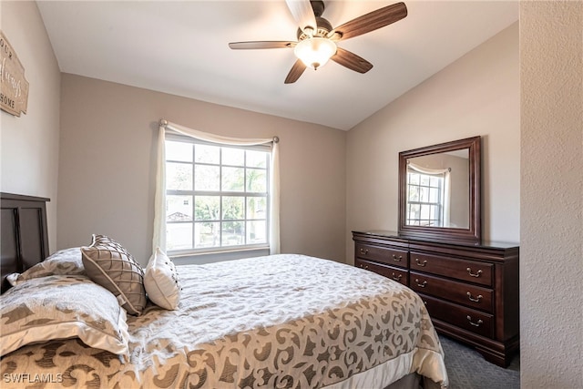 bedroom featuring lofted ceiling, dark colored carpet, and a ceiling fan