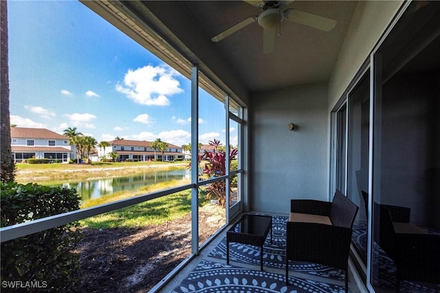 sunroom featuring a water view and a ceiling fan