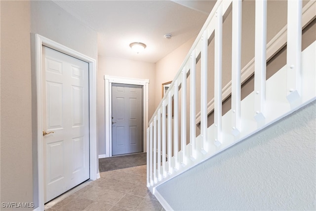 entrance foyer with tile patterned flooring, stairway, and baseboards