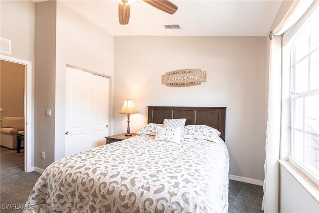 bedroom with baseboards, visible vents, dark colored carpet, and a closet