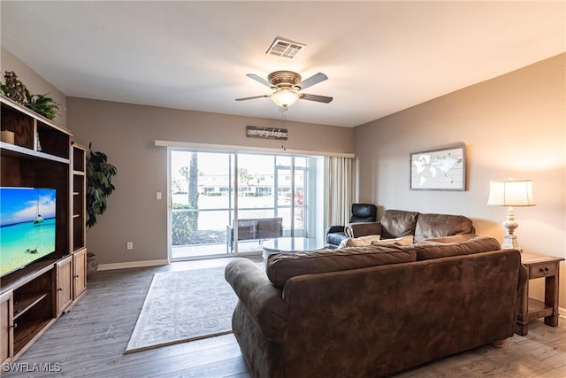 living area featuring a ceiling fan, baseboards, visible vents, and wood finished floors