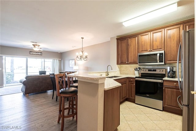 kitchen with a breakfast bar area, stainless steel appliances, a peninsula, a sink, and open floor plan