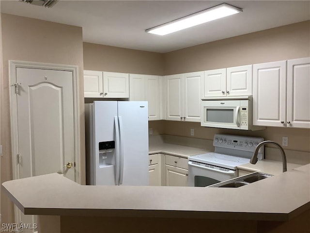 kitchen with white appliances, kitchen peninsula, and white cabinets