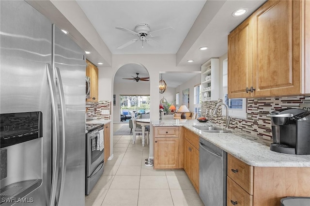 kitchen with stainless steel appliances, light stone counters, light tile patterned floors, sink, and kitchen peninsula