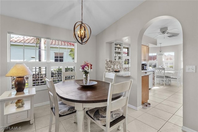 tiled dining area featuring ceiling fan with notable chandelier and vaulted ceiling