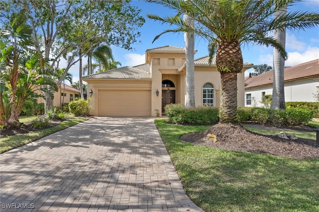 mediterranean / spanish home with a garage, a tiled roof, decorative driveway, and stucco siding