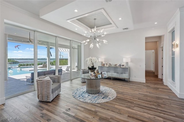 living area featuring recessed lighting, a raised ceiling, wood finished floors, baseboards, and ceiling fan with notable chandelier