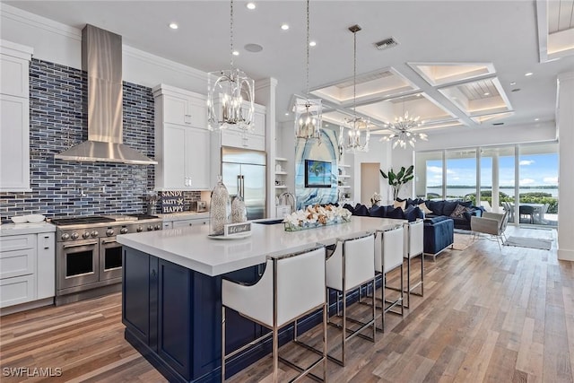 kitchen with a sink, visible vents, high quality appliances, light countertops, and wall chimney exhaust hood