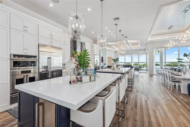 kitchen featuring beverage cooler, stainless steel appliances, visible vents, a large island, and an inviting chandelier