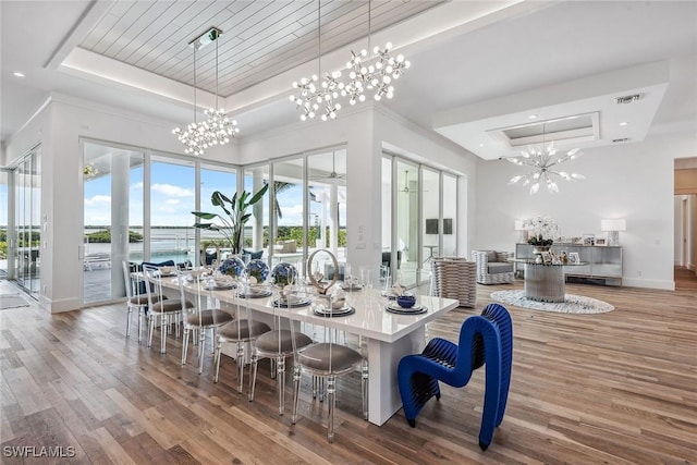 dining area with a chandelier, a raised ceiling, and wood finished floors