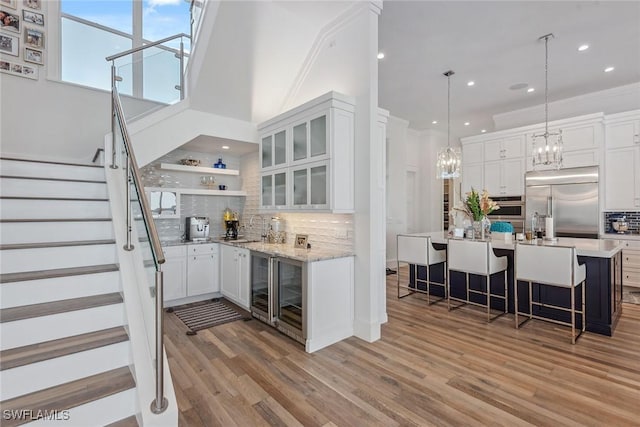 bar with appliances with stainless steel finishes, wine cooler, a sink, and stairway