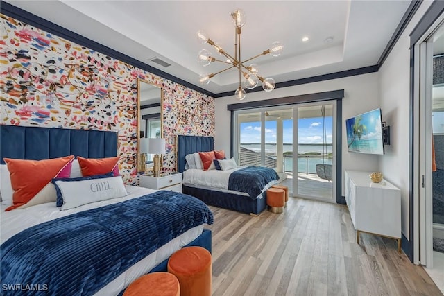 bedroom featuring wood finished floors, access to outside, a tray ceiling, crown molding, and a chandelier